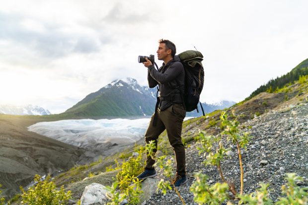 Chris Burkard debout sur une montagne se préparant à prendre une photo avec son appareil photo